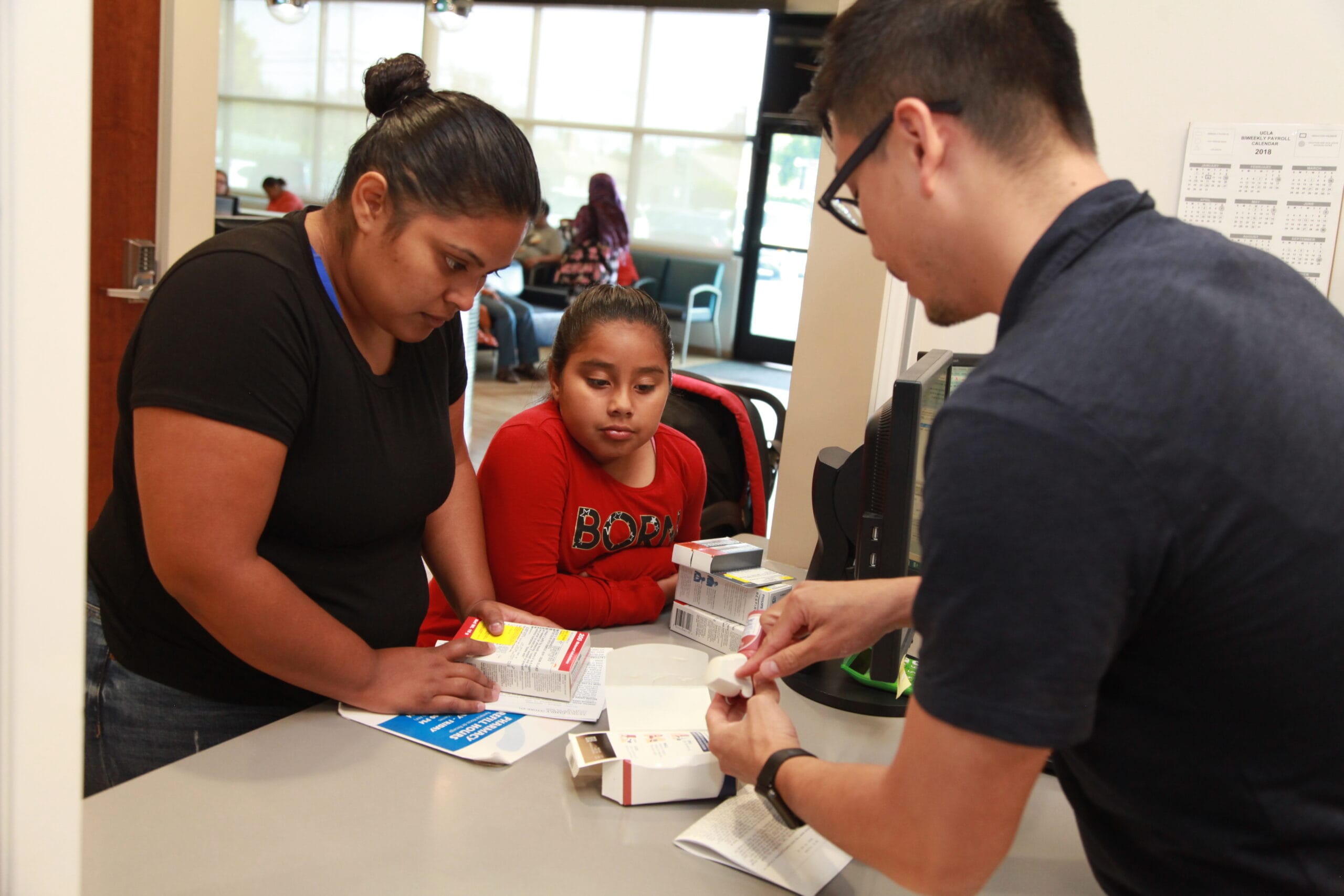 A mother and her child filling a pharmacy prescription.